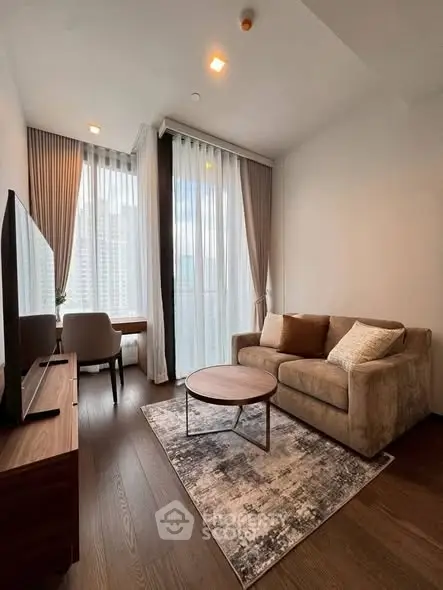 Modern living room with cozy sofa, stylish rug, and large windows offering city views.