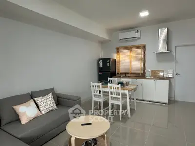 Modern open-layout living room with dining area and kitchen, featuring sleek furniture and neutral tones.