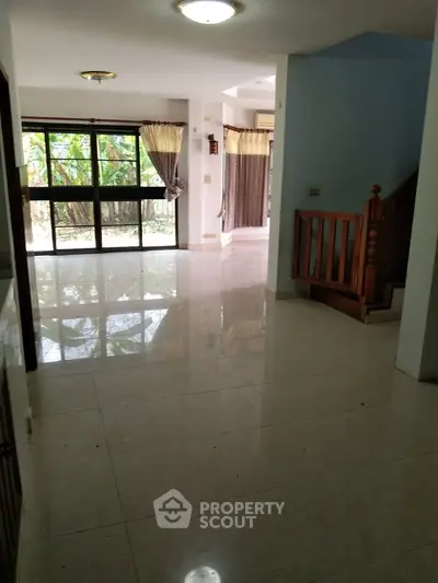 Spacious living room with large windows and elegant staircase in modern home