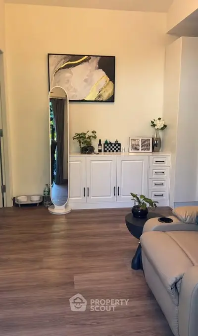 Stylish living room with modern decor and elegant furnishings, featuring a sleek floor mirror and chic artwork.