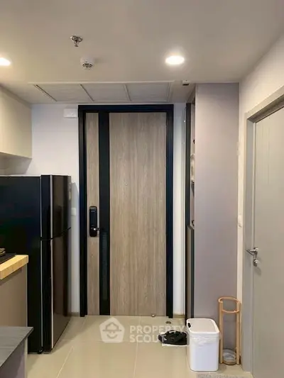 Modern apartment entrance with sleek black fridge and minimalist decor