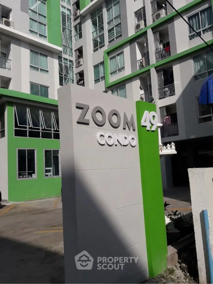Modern condominium building with green accents and prominent signage in urban setting.