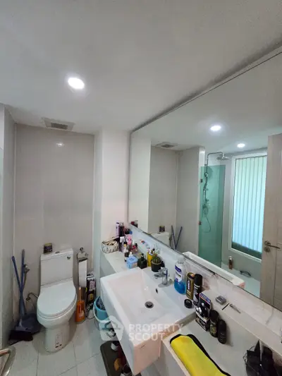 Modern bathroom with sleek fixtures and large mirror, featuring a shower and ample counter space.