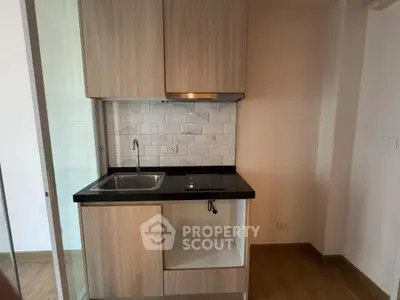 Modern compact kitchen with sleek cabinetry and induction cooktop in a stylish apartment.