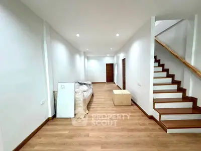 Spacious modern living room with wooden flooring and staircase, perfect for family gatherings.