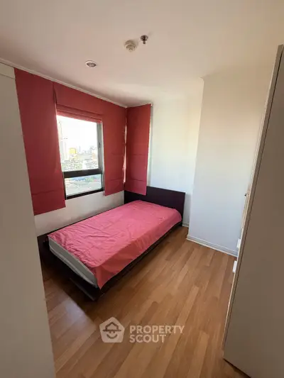 Cozy bedroom with single bed and city view, perfect for urban living.