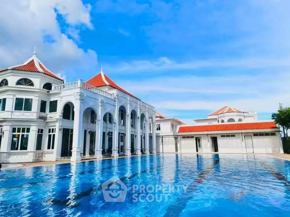 Luxurious mansion with stunning pool and elegant architecture under a clear blue sky.