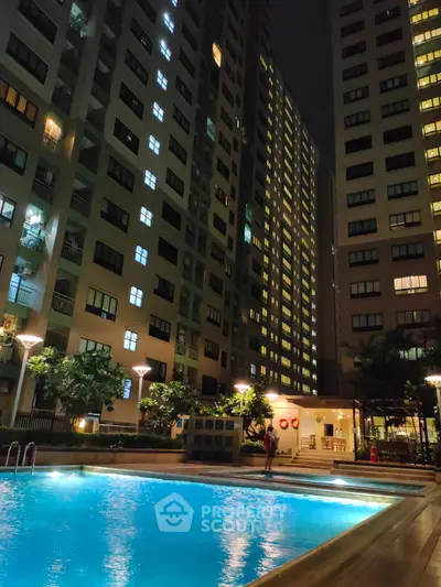 Stunning night view of a modern apartment complex with illuminated swimming pool.