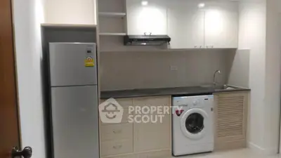 Modern kitchen with sleek appliances including fridge and washing machine, ideal for urban living.