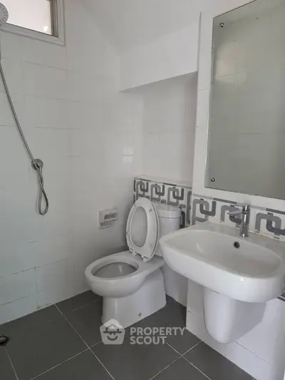 Modern bathroom with sleek white fixtures and geometric tile accents