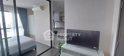 Modern apartment interior with bedroom and living area, featuring sleek design and natural light.