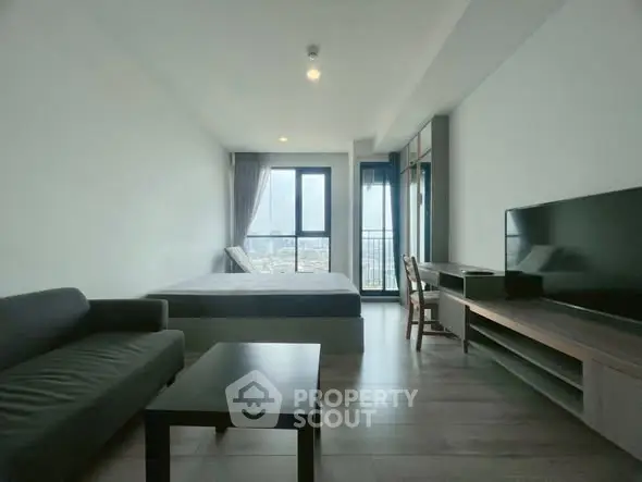 Modern studio apartment with large windows and city view, featuring a cozy living area and sleek furnishings.