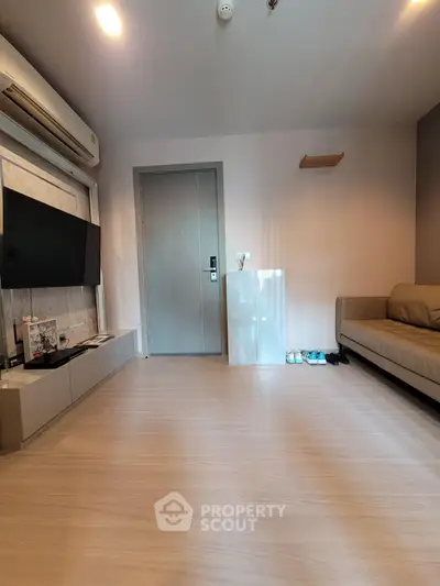 Modern living room with sleek design, featuring a wall-mounted TV, air conditioning, and stylish furniture.