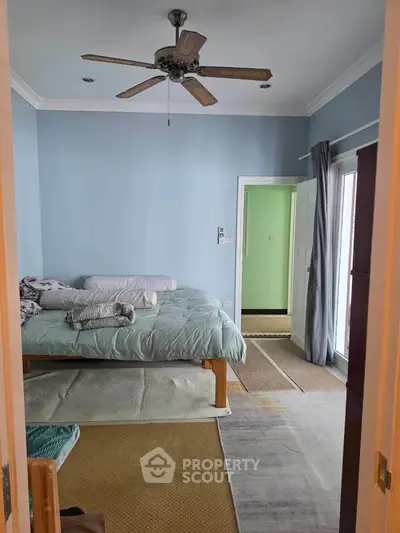 Cozy bedroom with ceiling fan and natural light, featuring a comfortable bed and soft color palette.