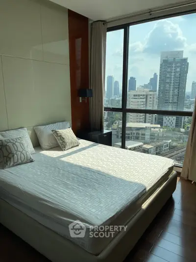 Modern bedroom with city view and large windows in high-rise apartment