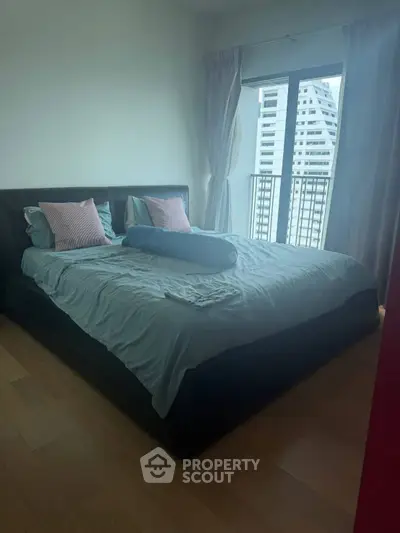 Cozy bedroom with large bed and city view from window, perfect for urban living.