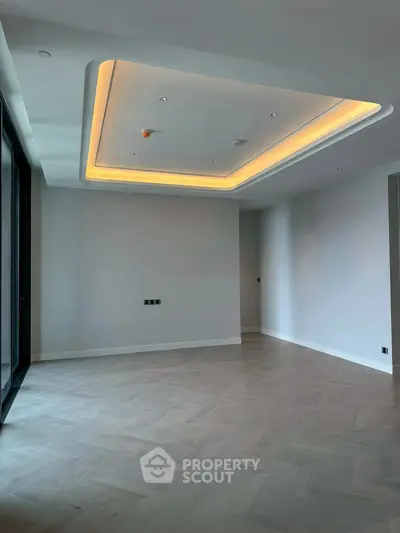 Spacious modern living room with elegant ceiling lighting and wooden flooring.