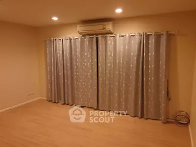 Spacious empty room with wooden flooring and air conditioning, perfect for customization.