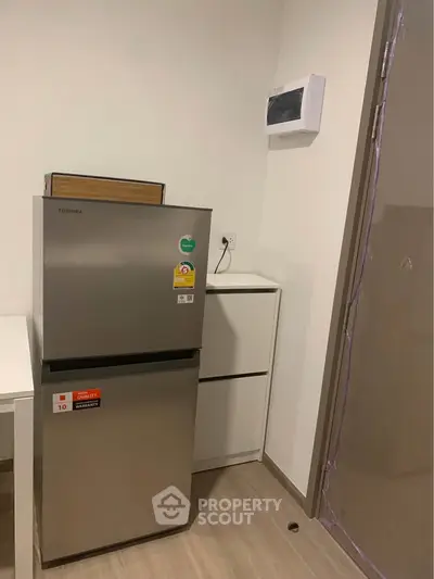 Modern kitchen corner with sleek fridge and minimalist storage cabinet.