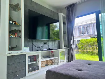 Modern living room with large TV and garden view, showcasing stylish interior design and natural light.
