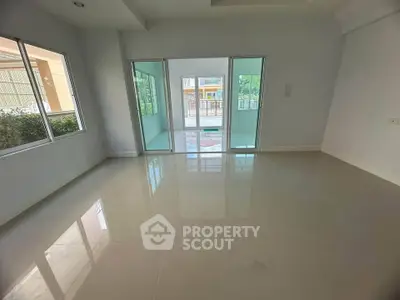 Spacious empty room with large windows and sliding glass doors leading to a balcony.