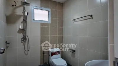 Modern bathroom with shower and toilet in tiled interior.