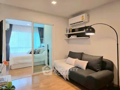 Modern living room with cozy sofa and view into stylish bedroom