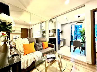 Modern living room with glass table and cozy sofa, open layout to dining area with balcony view.