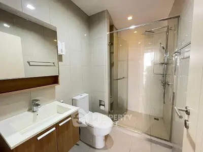 Modern bathroom with glass shower and sleek fixtures in contemporary apartment.