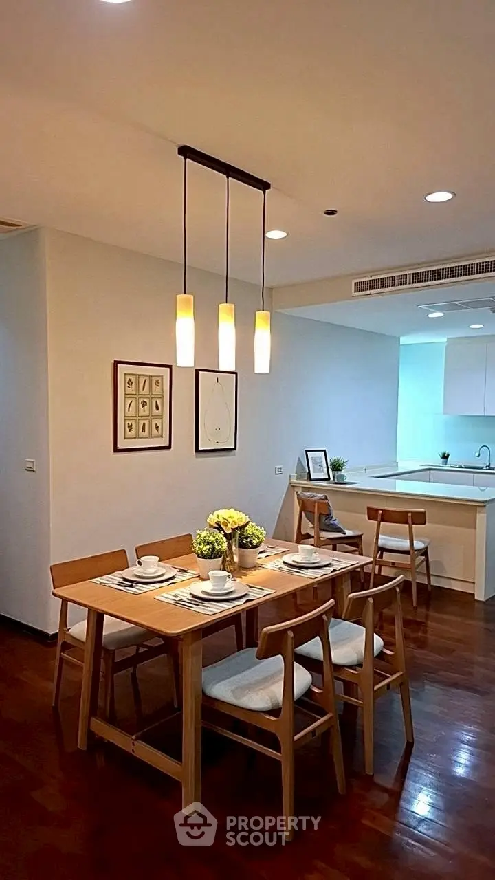 Modern dining area with elegant wooden table and chairs, adjacent to a sleek open kitchen layout.