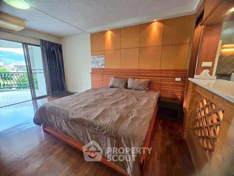 Spacious bedroom with wooden accents and balcony view in modern apartment