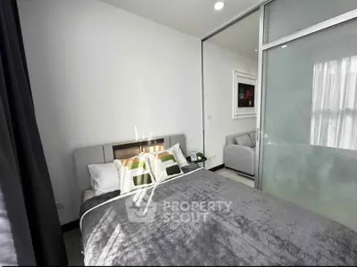 Modern bedroom with cozy bed and sliding glass door leading to a stylish living area.