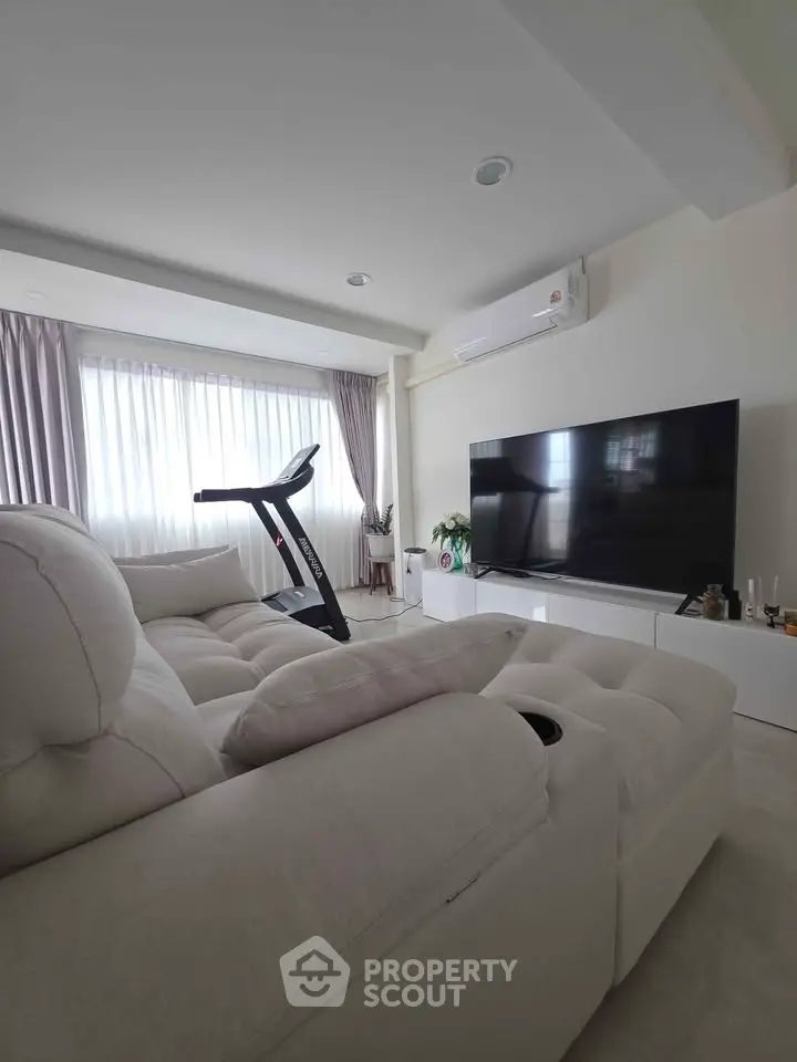 Spacious living room with modern decor, large TV, and exercise equipment, perfect for relaxation and fitness.