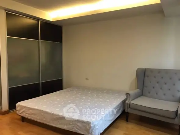 Spacious bedroom with modern sliding wardrobe and cozy armchair