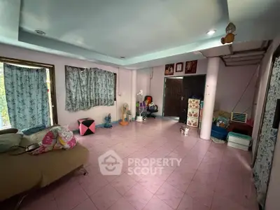 Spacious living room with pink tiled floor and cozy seating area, perfect for family gatherings.