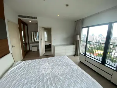 Spacious bedroom with city view and modern furnishings in high-rise apartment.
