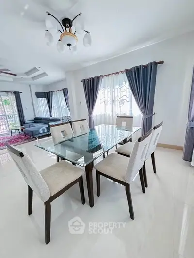 Elegant dining area with glass table and stylish chairs in a bright, modern living space.