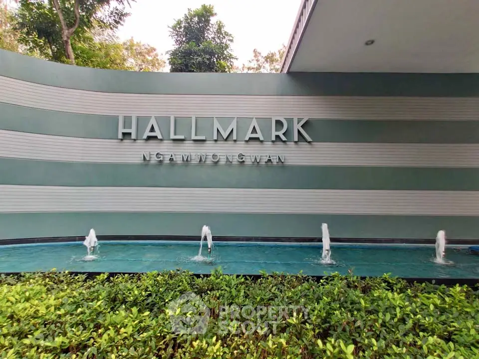 Elegant entrance of Hallmark Ngamwongwan with modern water feature and lush greenery.