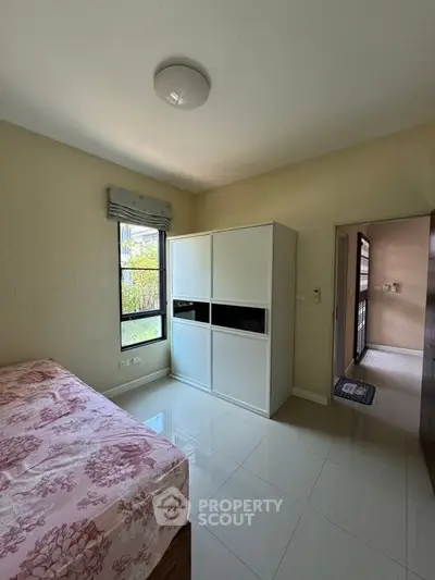 Bright bedroom with large window and modern wardrobe, perfect for cozy living.