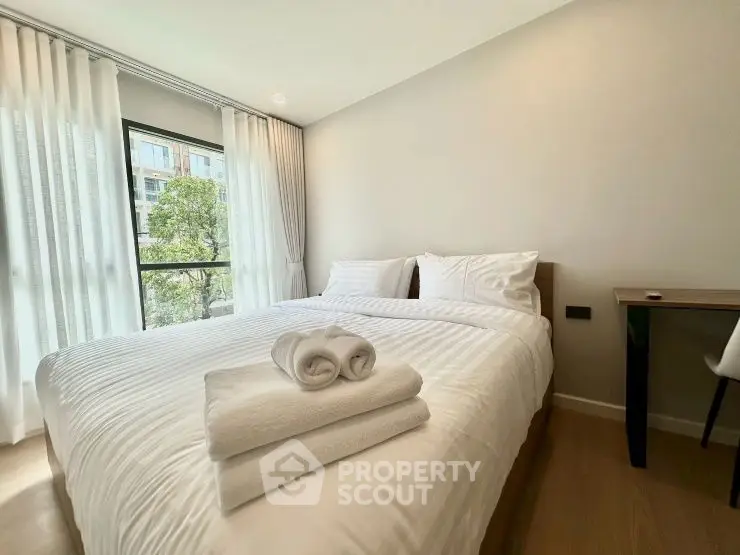 Bright and cozy bedroom with modern decor and large window view.