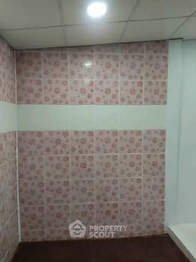 Charming bathroom with floral pink tiles and modern ceiling light.