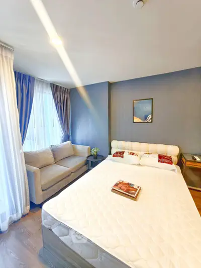 Cozy bedroom with elegant decor and natural light, featuring a comfortable bed and stylish sofa.