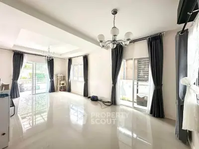 Spacious living room with elegant chandeliers and large windows for natural light.