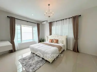 Elegant bedroom with plush bed, chandelier, and large windows for natural light.