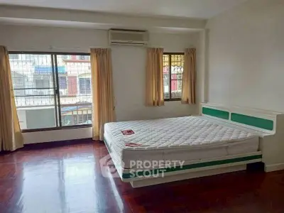 Spacious bedroom with large windows and hardwood floors in a well-lit apartment.