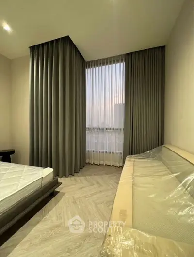 Modern bedroom with large window and elegant curtains, featuring a stylish bed and cozy seating area.