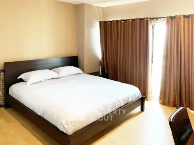 Spacious bedroom with large bed and elegant curtains in modern apartment.