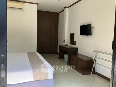Spacious bedroom with modern furnishings and wall-mounted TV in a stylish apartment.