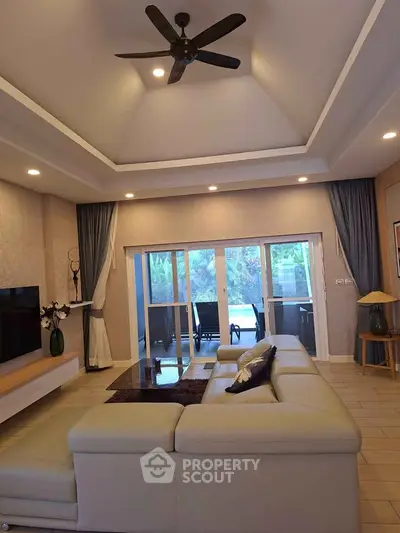 Spacious living room with modern decor and large windows opening to a lush garden view.