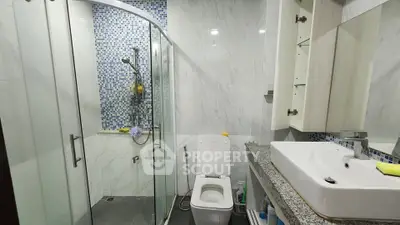 Modern bathroom with glass shower and sleek vanity in a stylish home.
